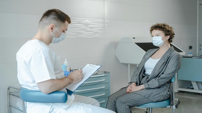 Un infirmier et une patiente portant un masque durant un entretien médical