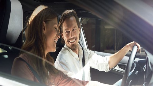 Couple souriant installé à l'avant d'une voiture
