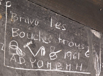 « Bravo les Bouches trous » ! Cri sarcastique poussé en 1961 contre le lavage (sceau et serpillère),  le nettoyage (balais) et la cuisine (casserole), photo Alain Besse (© Office du patrimoine et des sites)