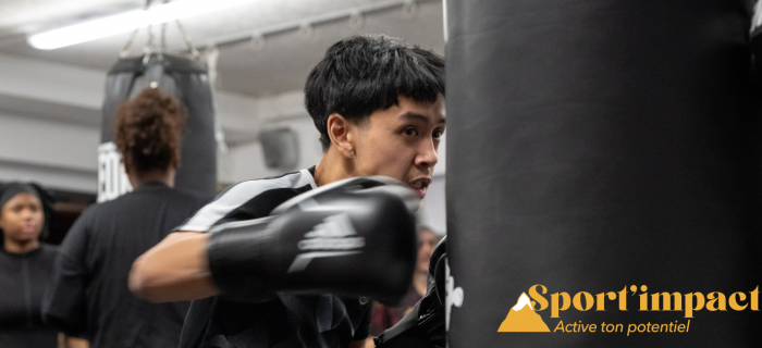 Un jeune tape dans un sac avec des gants de boxe 